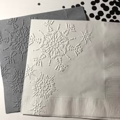 three napkins with snowflakes on them are sitting next to each other in black and white