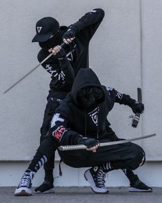 two people in black hoodies holding swords