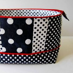 a black and white polka dot bag with red trimmings on the bottom, sitting on a table