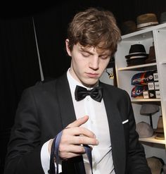 a young man in a tuxedo looking down at his tie