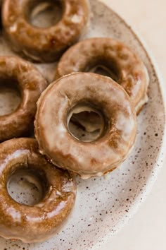 four glazed donuts on a plate with sprinkles