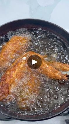 two pieces of meat cooking in a frying pan with water on the stove top