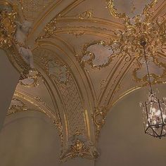 a chandelier hanging from the ceiling in a room with gold and white walls