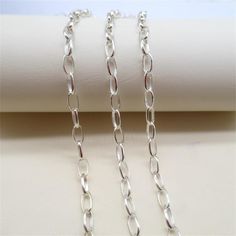 two pieces of silver chain sitting on top of a table