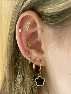 a woman wearing three different ear piercings on her left ear and one with an animal's paw