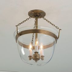 a light fixture hanging from the ceiling with three lights on it's sides and two small candles in between them