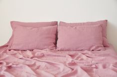 a bed with pink sheets and pillows on it