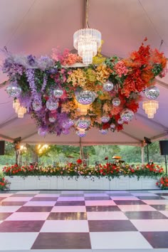 an indoor dance floor decorated with flowers and chandeliers