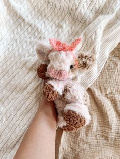 a small stuffed animal laying on top of a bed next to a person's arm