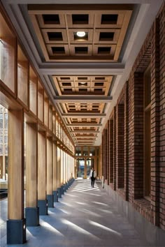 a person walking down a long hallway between two tall brick buildings with windows on each side