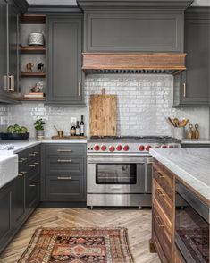 a kitchen with gray cabinets and white marble counter tops is featured in the instagram