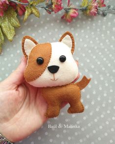 a hand holding a small brown and white stuffed animal