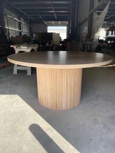 an oval wooden table sitting inside of a warehouse