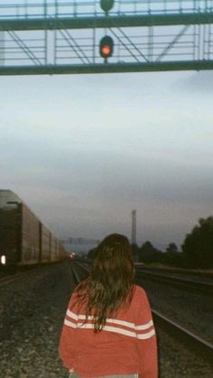 a woman standing on the train tracks at dusk