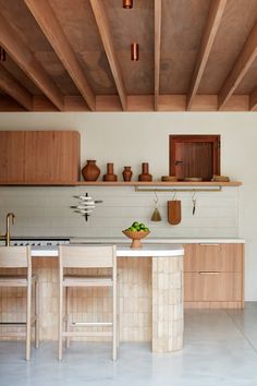 a kitchen with wooden cabinets and white counter tops, along with two stools in front of the island