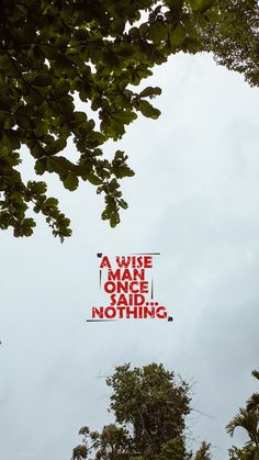 a red sign hanging from the side of a tree in front of a cloudy sky