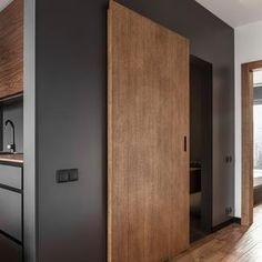 an open door in the middle of a room with wood floors and black painted walls