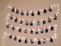 several polaroid photos are hung on clothes pins with string lights strung from the wall