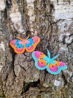 two crocheted butterflies sitting on the bark of a tree