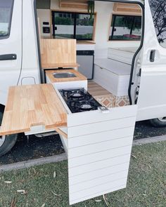 a small camper van with the door open and wood counter tops on it's side