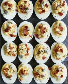 deviled eggs topped with bacon and cheese on a baking sheet, ready to be baked