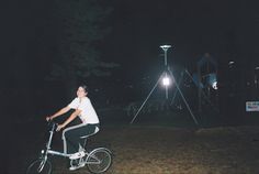 a man riding a bike at night with the lights on in the dark behind him