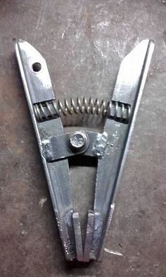 a pair of scissors that are sitting on the ground next to some screws and nails