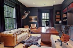 an office with leather furniture and deer heads on the wall, along with bookshelves