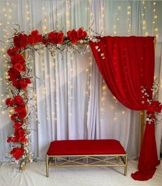 a red and white wedding setup with flowers on the wall, drapes and lights in the background