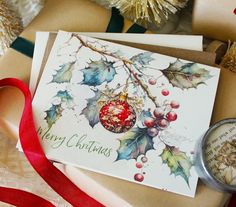 a christmas card with holly and baubles on it, next to a compass