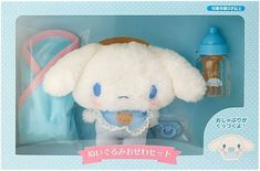 a white stuffed animal with blue eyes in a toy box next to a baby bottle