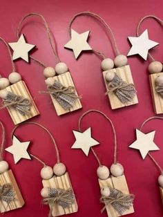 wooden stars and ornaments hang from twine on a red wall, with string attached to them