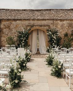 an outdoor ceremony with white chairs and flowers