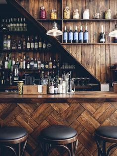 a bar with stools and shelves filled with bottles