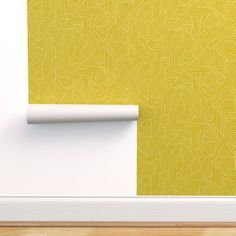 an empty room with a yellow wallpaper and white trim on the wall, next to a roll of tape