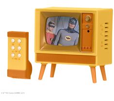 an old fashioned television with batman and robin wayne on it's stand next to a remote control