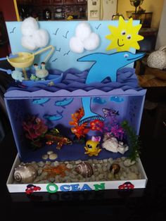 an aquarium with rocks, gravel and plastic toys in it's bottom shelf on a table