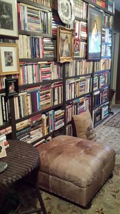 a living room filled with lots of books on the wall and a chair in front of it