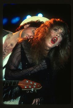 two people with long hair and one is holding a guitar