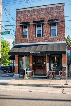 an old brick building with awnings and tables outside on the sidewalk in front of it