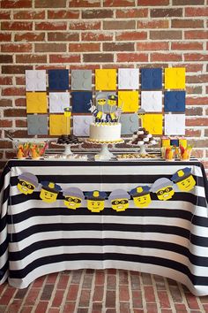 a table topped with a cake covered in legos on top of a brick wall