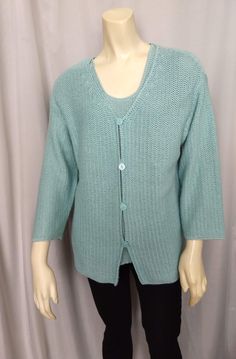 a mannequin wearing a green sweater and black leggings with a white button on the front