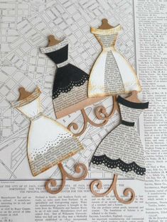 three paper dolls are sitting on top of a piece of paper that is cut out to look like dresses