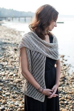 a woman is standing on the beach wearing a shawl