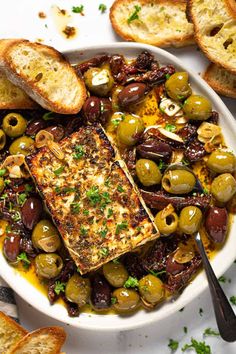 a white plate topped with olives, bread and anchovies on top of it