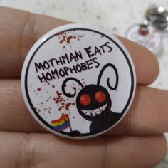 a button with the words mothman eats homophobias on it