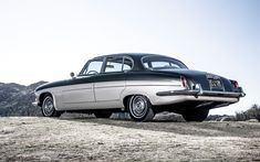 an old black and white car parked on top of a hill