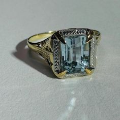 The aqua is approximately 1.1 carat with a beautiful medium blue hue, and a shimmering emerald cut. The ring measures 12mm wide with a rise of 6mm, and the shank is 1mm Marked 10K OB Very good condition Art Deco Aquamarine Ring, Aquamarine Ring, Aquamarine Rings, Filigree Ring, Ring Size 7, 1 Carat, Blue Hues, Emerald Cut, Rings Statement