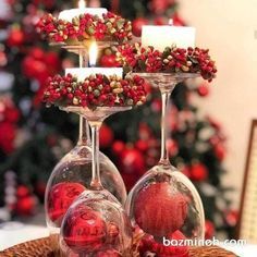 two wine glasses filled with red berries and candles