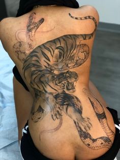 the back of a woman with tattoos on her body and an image of a tiger